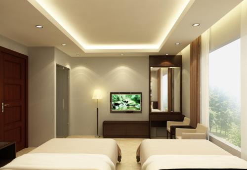a bedroom with two beds and a tv on the wall at Green Hotel in Hanoi