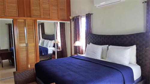 a bedroom with a blue bed and two mirrors at White Sands Anguilla - Sea in Blowing Point Village