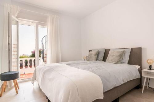 a white bedroom with a large bed and a window at Casa Alegría Nerja in Nerja