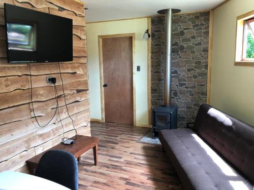 uma sala de estar com um sofá e um fogão a lenha em Cabanas Senderos Puyuhuapi em Puerto Puyuhuapi