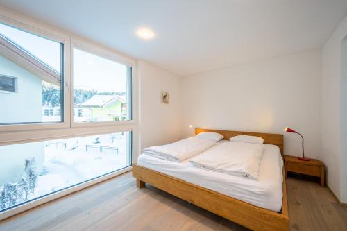 a bedroom with a bed and a large window at Casa Mutta in Laax