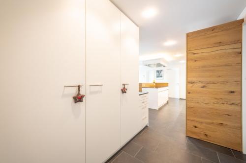 a kitchen with white cabinets and a wooden door at Casa Mutta in Laax