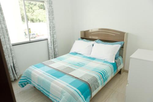 a bedroom with a bed with blue and white sheets at Apartamento 2 quartos in Laguna