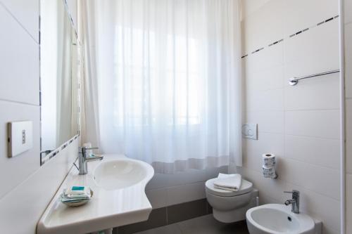 a white bathroom with a sink and a toilet at Hotel Savana in Rimini