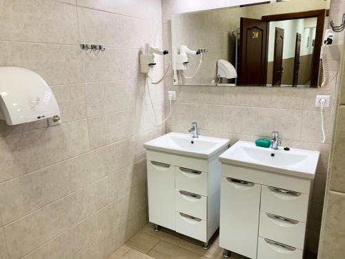La salle de bains est pourvue de 2 lavabos et d'un miroir. dans l'établissement Hostel Gulliver, à Oujhorod