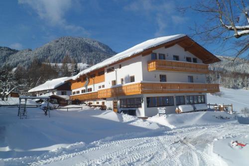 a building with snow on the ground in front of it at Berggasthaus Kraxenberger in Brannenburg