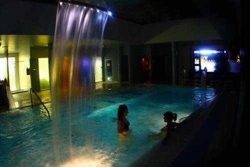 two children in a swimming pool with a fountain at Hotel Balneario Valle del Jerte in Valdastillas