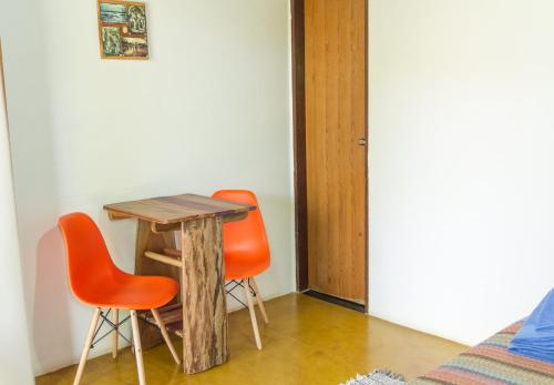 uma mesa e duas cadeiras laranjas num quarto em Pousada Jardim da Nova Era em Alto Paraíso de Goiás
