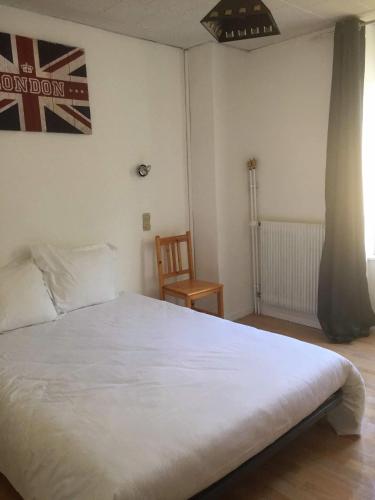 a bedroom with a large white bed and a chair at Hôtel de Londres in Le Mont-Dore