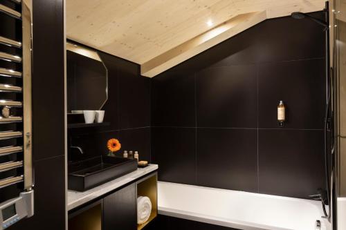 a bathroom with black walls and a sink at St-Alban Hotel & Spa in La Clusaz