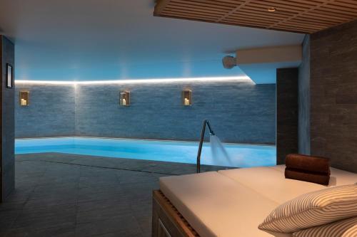 1 dormitorio con piscina, cama y silla en St-Alban Hotel & Spa en La Clusaz
