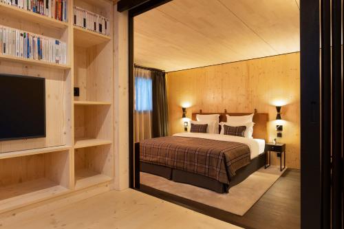 a bedroom with a bed and a tv and shelves at St-Alban Hotel & Spa in La Clusaz