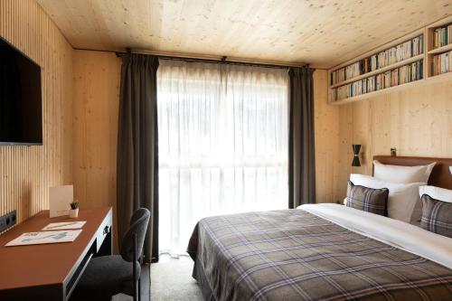 a bedroom with a bed and a desk and a window at St-Alban Hotel & Spa in La Clusaz