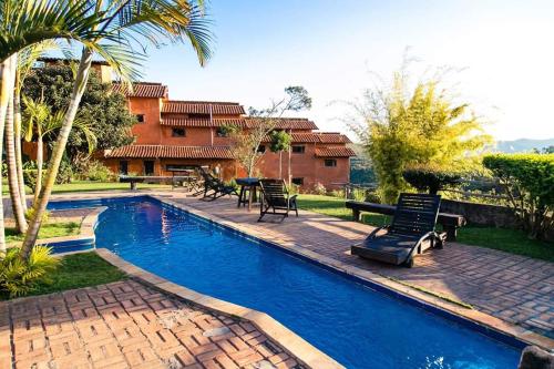 a swimming pool in a yard with chairs and a house at Pousada Buieié in Lavras Novas