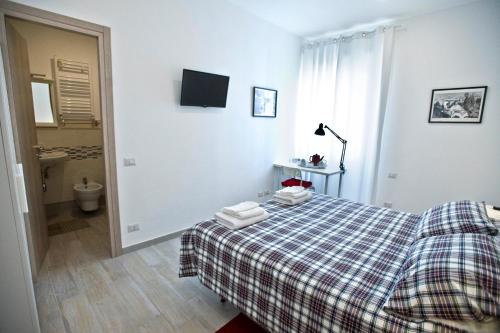 a bedroom with a bed with a plaid blanket and a bathroom at Fellini in Rome