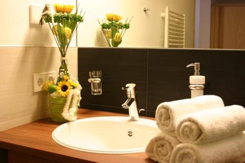 ein Waschbecken mit Handtüchern und eine Vase Blumen in der Unterkunft Hotel Mall in Sankt Valentin auf der Haide