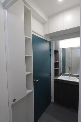 baño con puerta azul y lavamanos en Le Continental, en Cayeux-sur-Mer