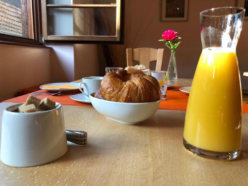 a table with a bowl of bread and a glass of orange juice at Le Grenier Des Arômes Au Domaine Wittmann in Mittelbergheim