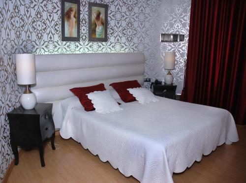 a bedroom with a white bed with two red pillows at Hotel Villa de Cacabelos in Cacabelos