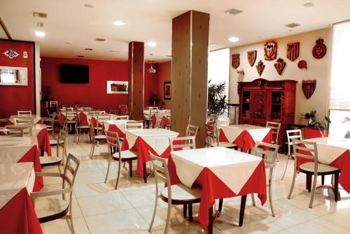 Hotel Villa de Cacabelos في كاكابيلوس: مطعم بجدران حمراء وطاولات بيضاء وكراسي
