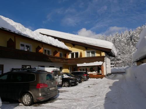 a car parked in front of a building with snow at Pension Haus in der Sonne in Fieberbrunn