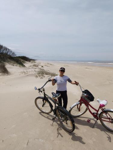 a man standing with two bikes on the beach at Playa, bosque y lago in Montevideo