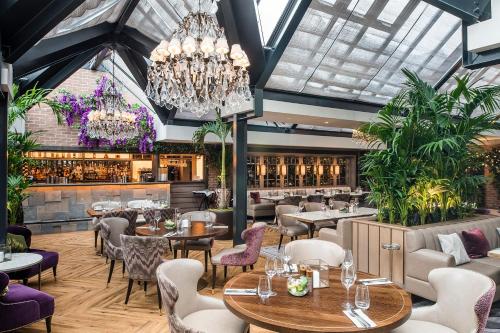 a restaurant with tables and chairs and a chandelier at Grosvenor Pulford Hotel & Spa in Pulford