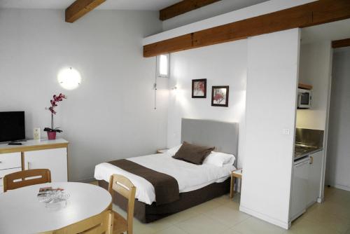 a bedroom with a bed and a table and a kitchen at Résidences Guerlin in Toulouse