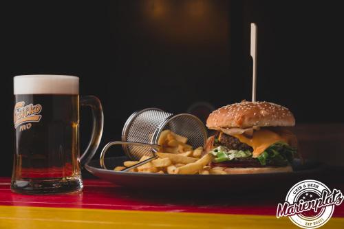 a plate with a sandwich and french fries and a glass of beer at Hotel Marienplatz Podgorica in Podgorica