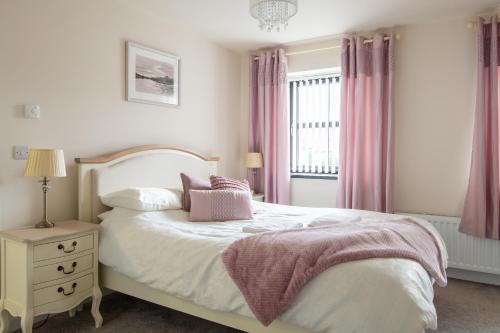 a bedroom with a bed and a window with pink curtains at New In Newcastle in Newcastle