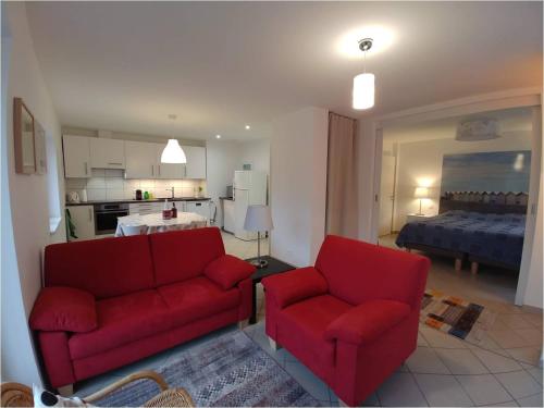 a living room with two red couches and a kitchen at Gîtes du Tilleul in Niederbronn