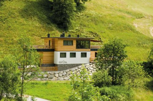 a house on a hill with a stone wall at Chalet Glemmtal - Haus Schmittenblick in Viehhofen