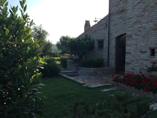 a backyard of a brick house with red flowers at La Villa degli Ulivi in Fermo