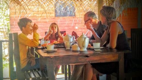 a group of people sitting around a wooden table at Eco Cabanas Marakolliya in Tangalle