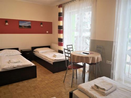 Zimmer mit 2 Betten, einem Tisch und einem Fenster in der Unterkunft Leniwy Motyl in Rajcza