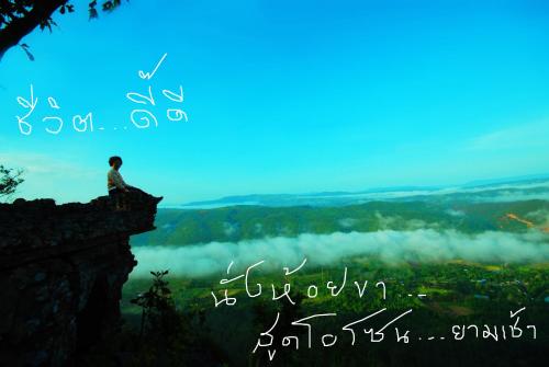 a man sitting on the edge of a cliff on a mountain at Pupiang po Da Arte Resort in Dan Sai