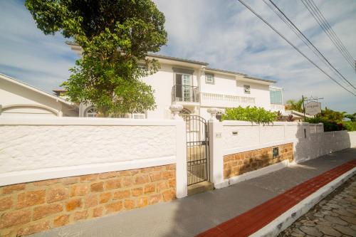 a white house with a brick wall and a fence at Solar Beach Hotel in Florianópolis