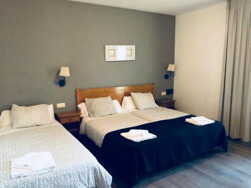 two beds in a hotel room with towels on them at Hotel Avenida del Sotillo in La Lastrilla