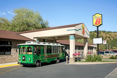 a green bus parked in front of a gas station at Super 8 by Wyndham Deadwood Black Hills Area in Deadwood