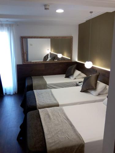 a hotel room with two beds with a mirror and a mirror at Moderno in Barcelona