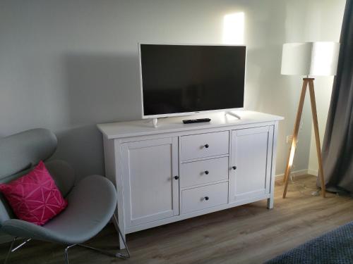a white dresser with a television on top of it at Swiss Seeblick Apartment mit Hotelanbindung in Beatenberg