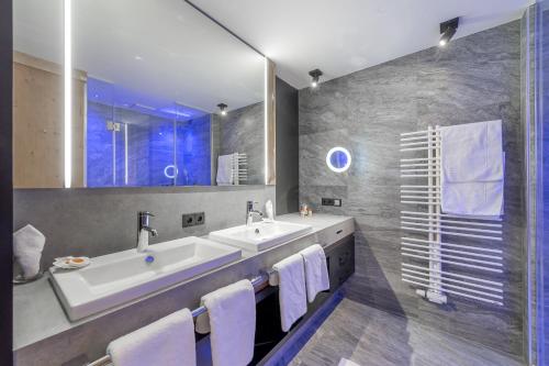 baño con 2 lavabos y espejo grande en Aktiv- & Wellnesshotel Bergfried en Tux