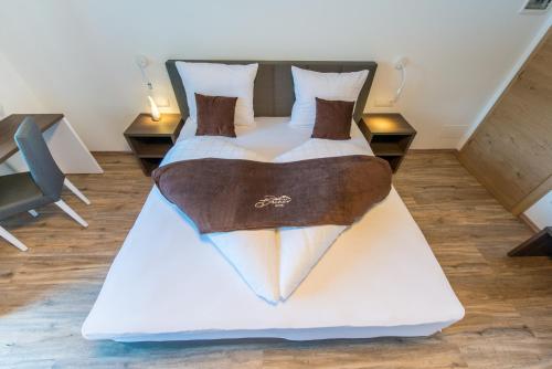 a bedroom with a large bed with a large white bedspread at Hotel Bacher in Riva di Tures