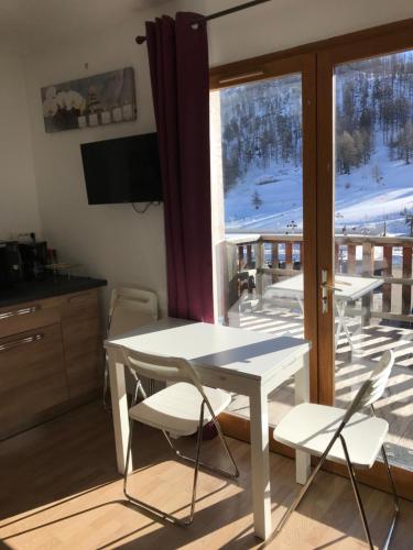 モンジェネヴルにあるMontgenevre Neige et Golf coquet studio 4 pers maxiのテーブルと椅子、バルコニーが備わる客室です。