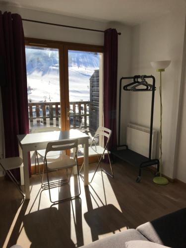 モンジェネヴルにあるMontgenevre Neige et Golf coquet studio 4 pers maxiのテーブルと椅子、窓が備わる客室です。