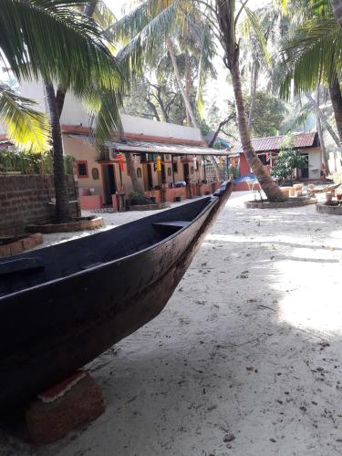 a boat sitting on a beach with palm trees at Sai Homestay in Malvan