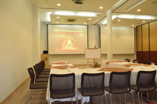 a conference room with tables and chairs and a screen at Hotel Union in Girardot