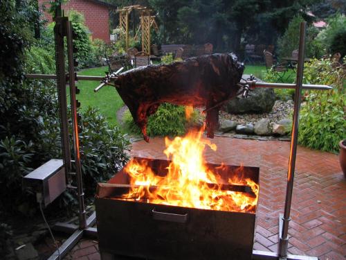 a fire pit in a yard with a chicken hanging over it at Heitmann`s Gasthof in Kirchlinteln