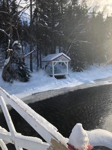 a gazebo in the snow next to a river at Chalet Le Semeur in Saint Elie