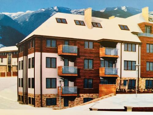 a building in the snow with mountains in the background at Chalet Mechka in Borovets